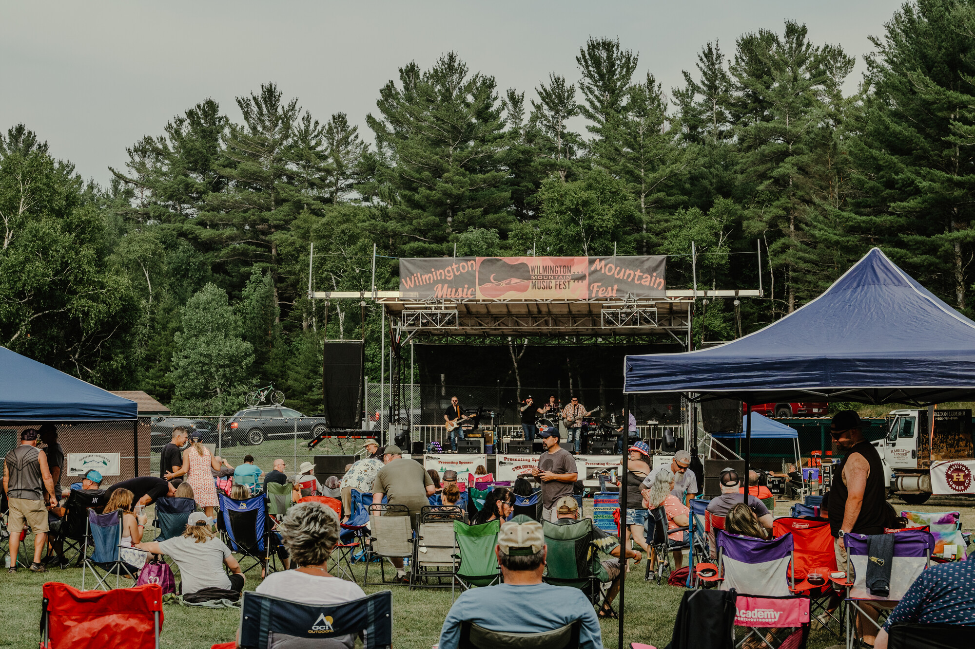A music festival with a stage and people in lawn chairs