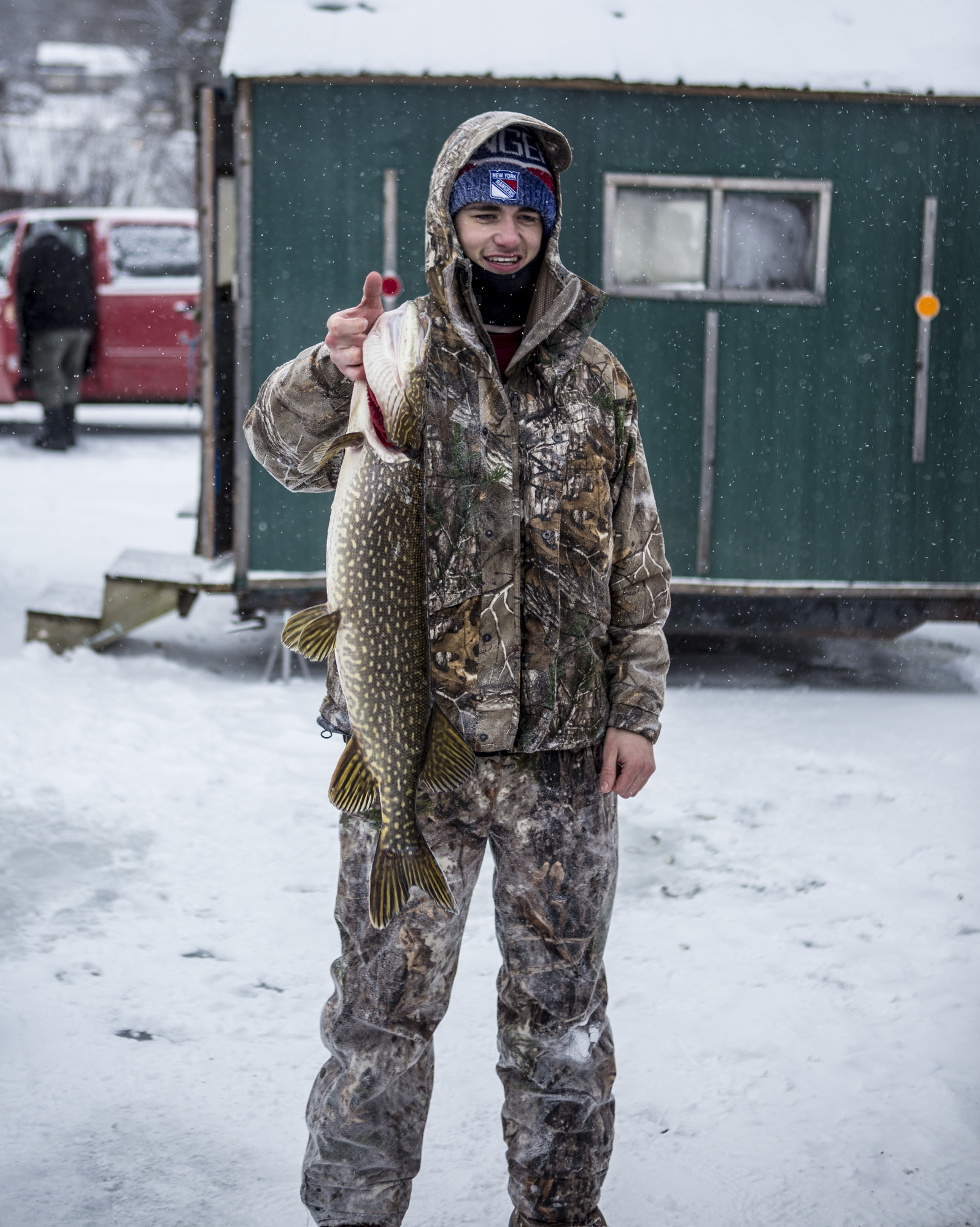 Someone in camo holding a northern pike