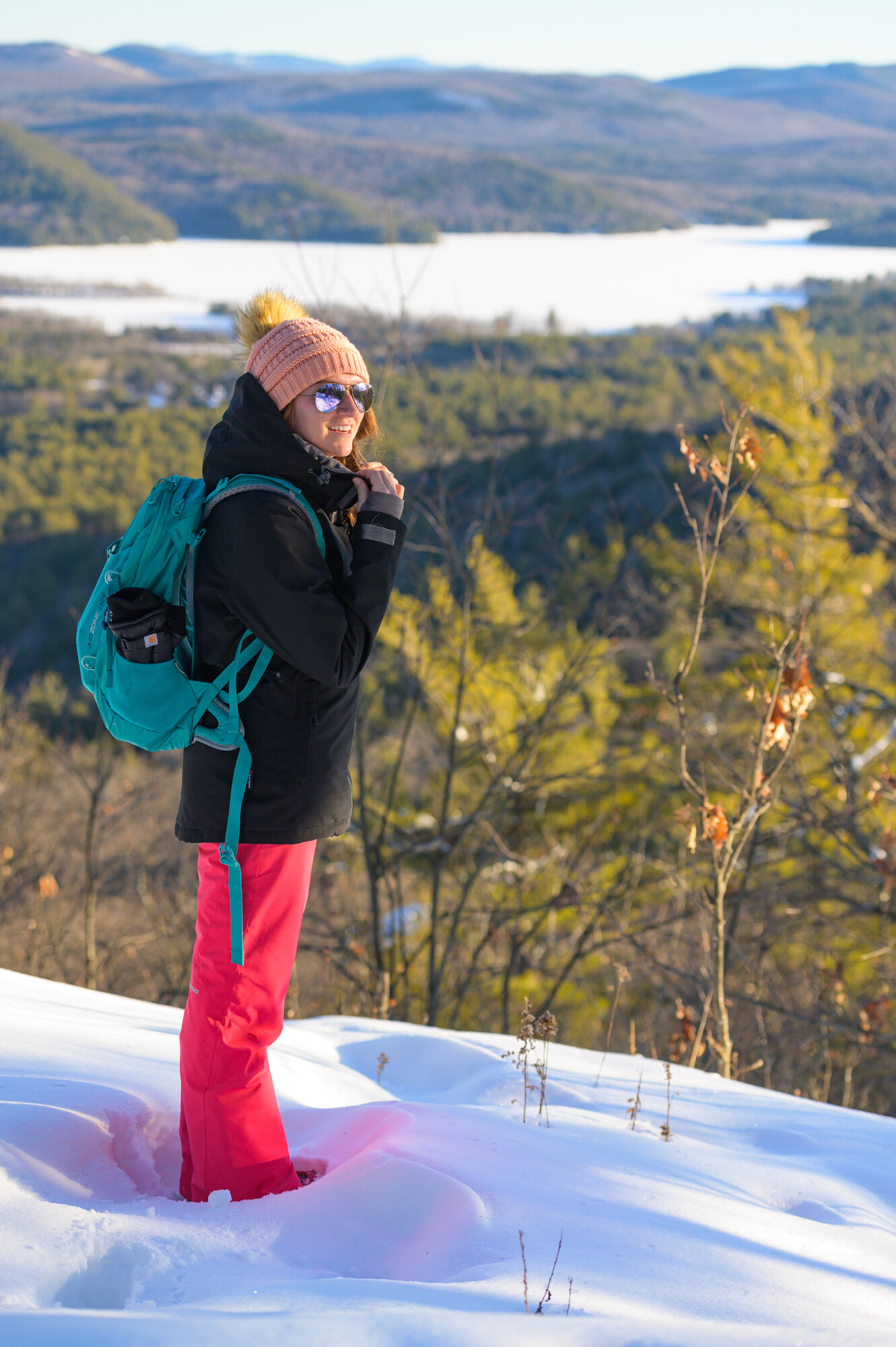 A women on a winter summit looking at a frozen lake