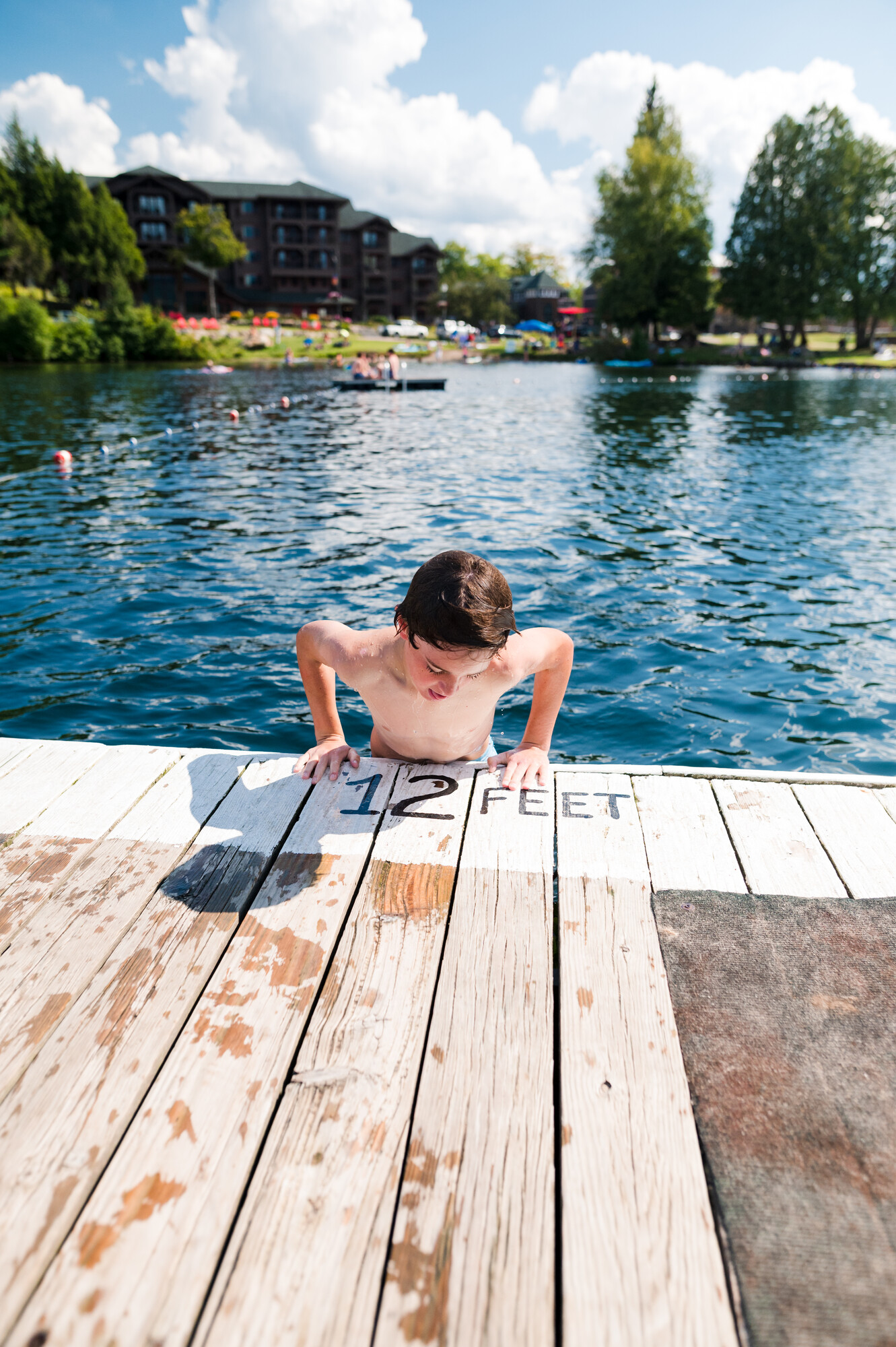 A kid getting out of the water onto a dock