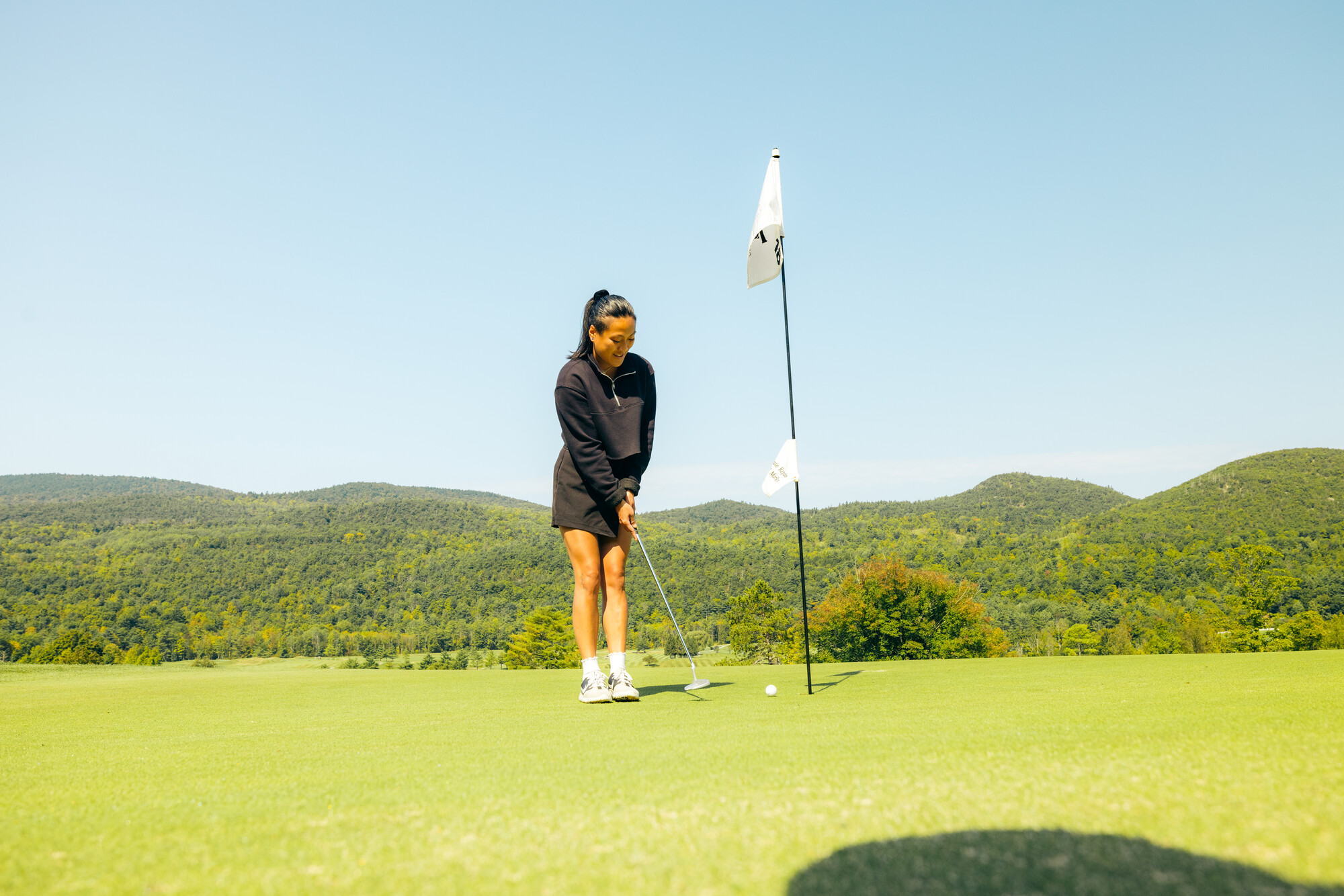 A woman golfing with mountains in view