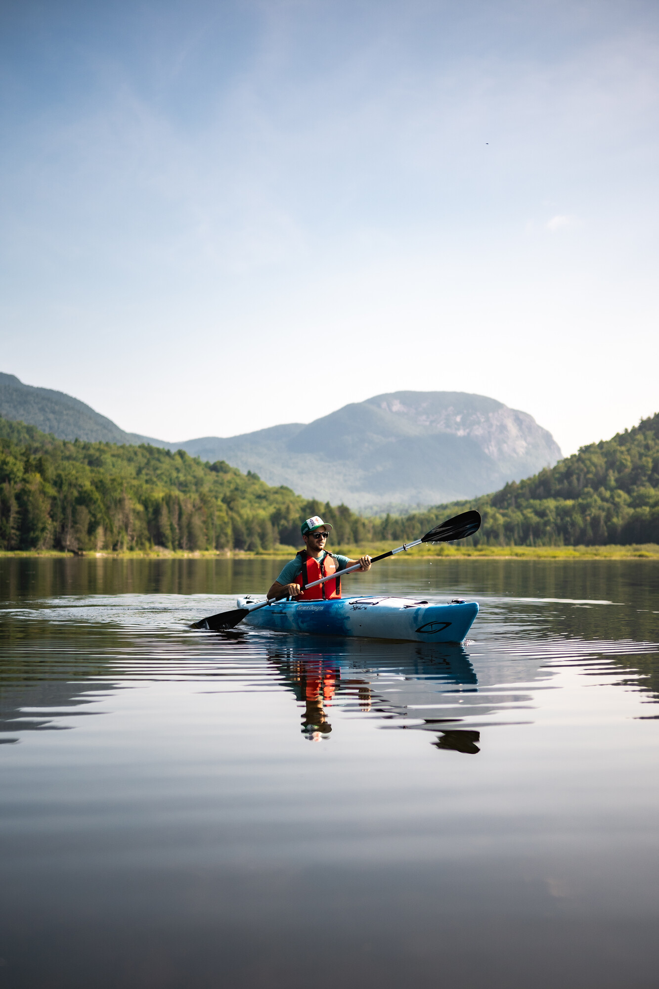 A kayaker on a mountain lake with a cliff in the background