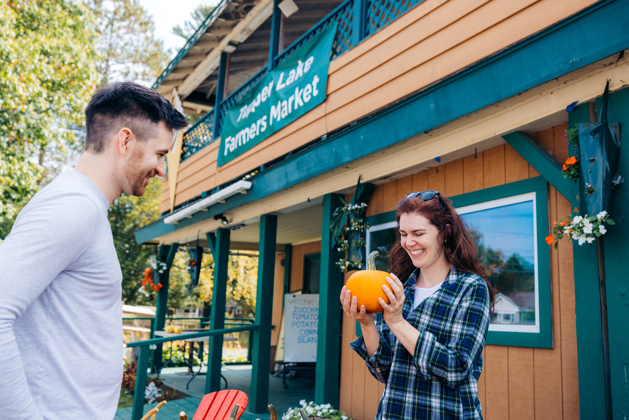 A couple looking at a pumpkin at a farmers' market