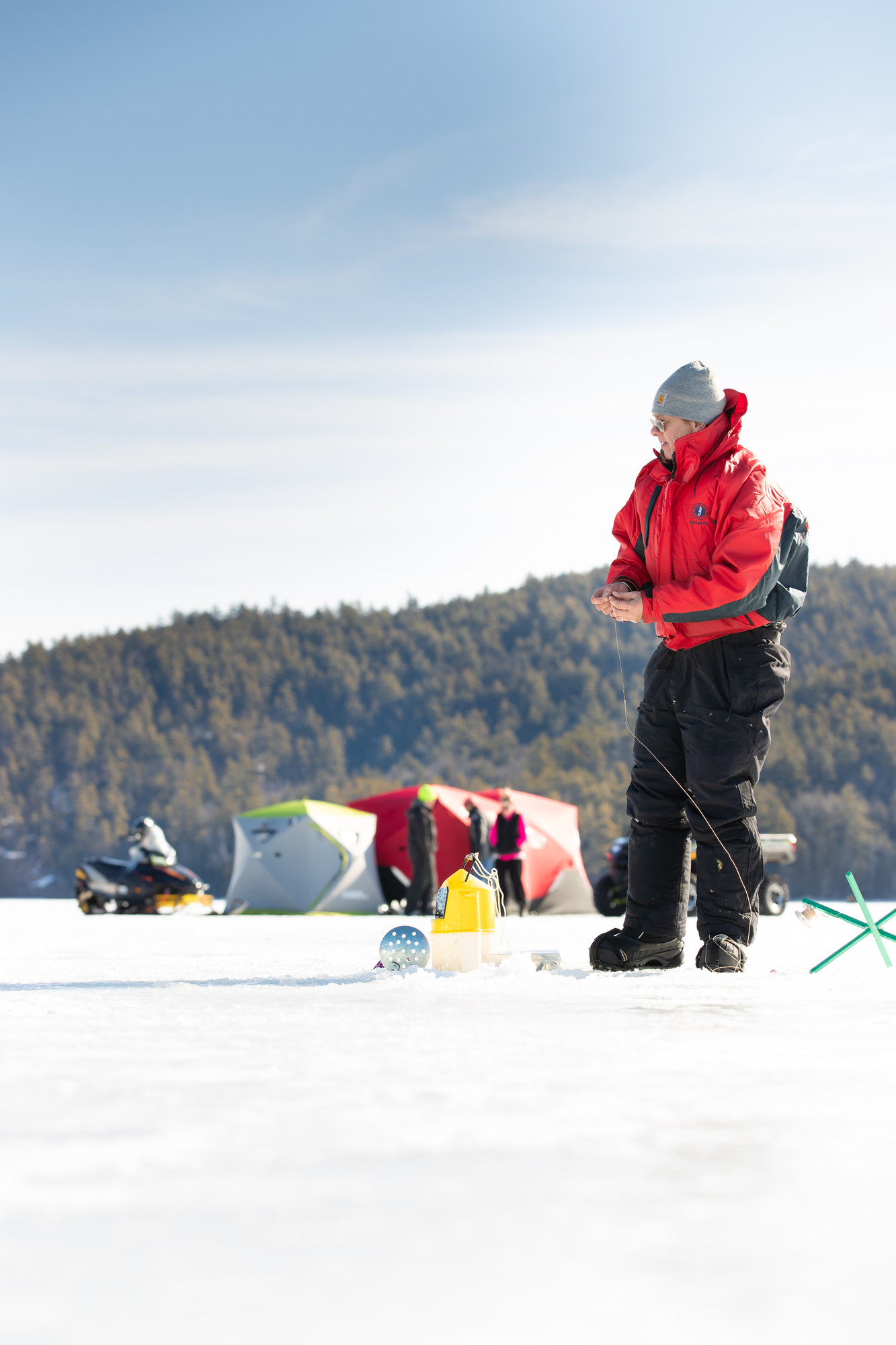 A guy ice fishing in a big red coat