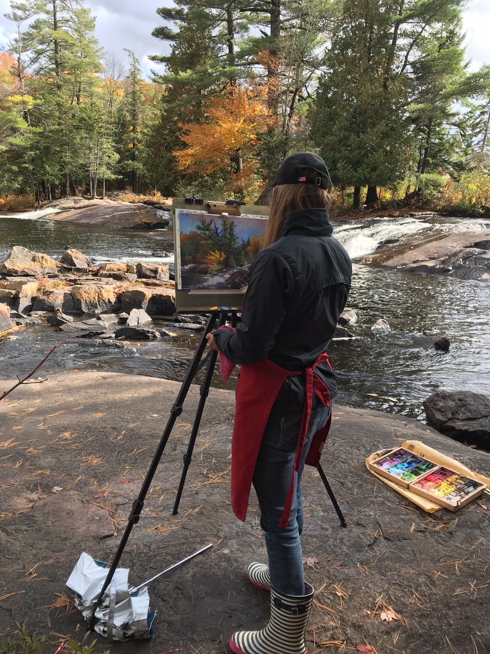 A plein air painter next to a river