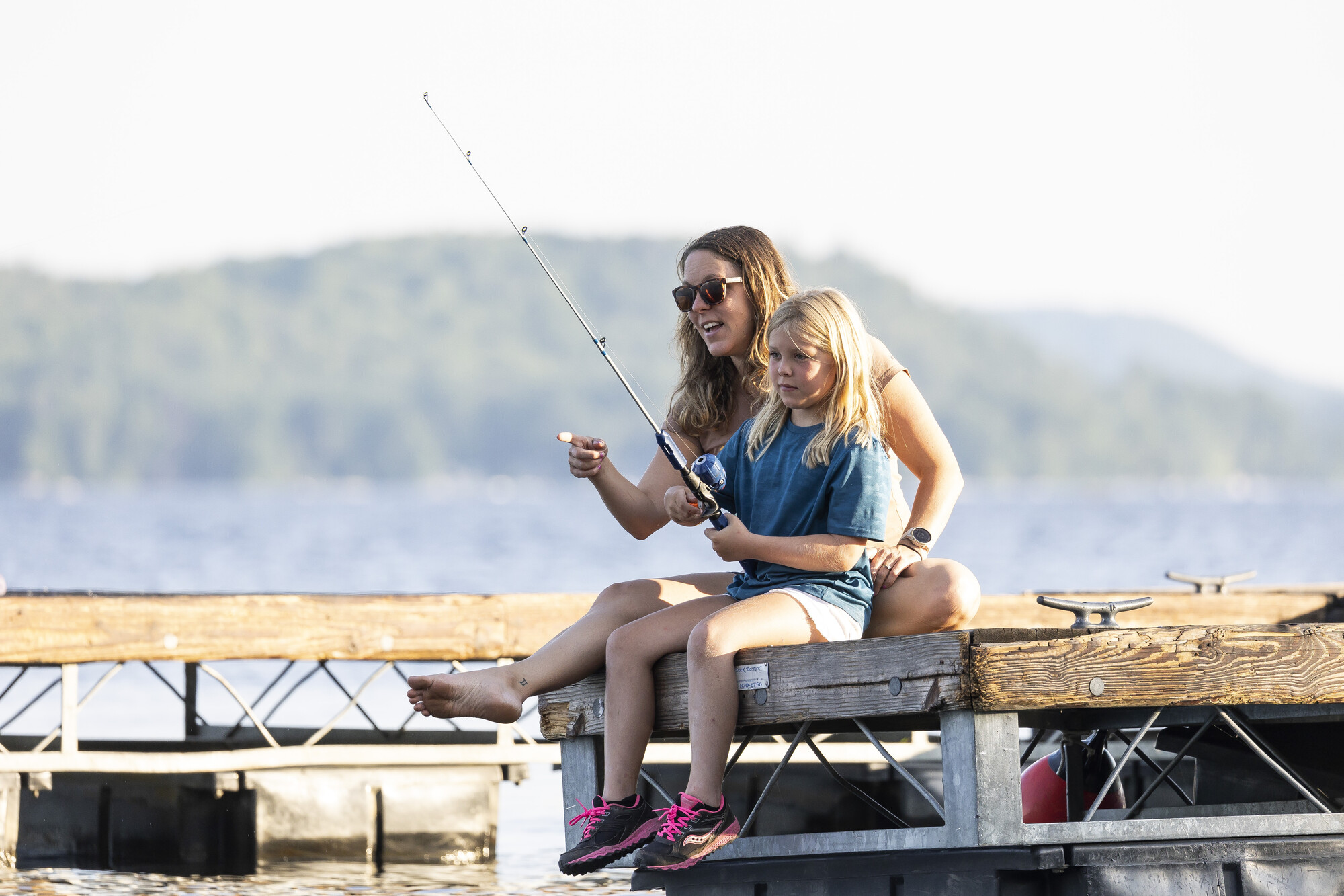 A mopther with her daughter fishing from a dock