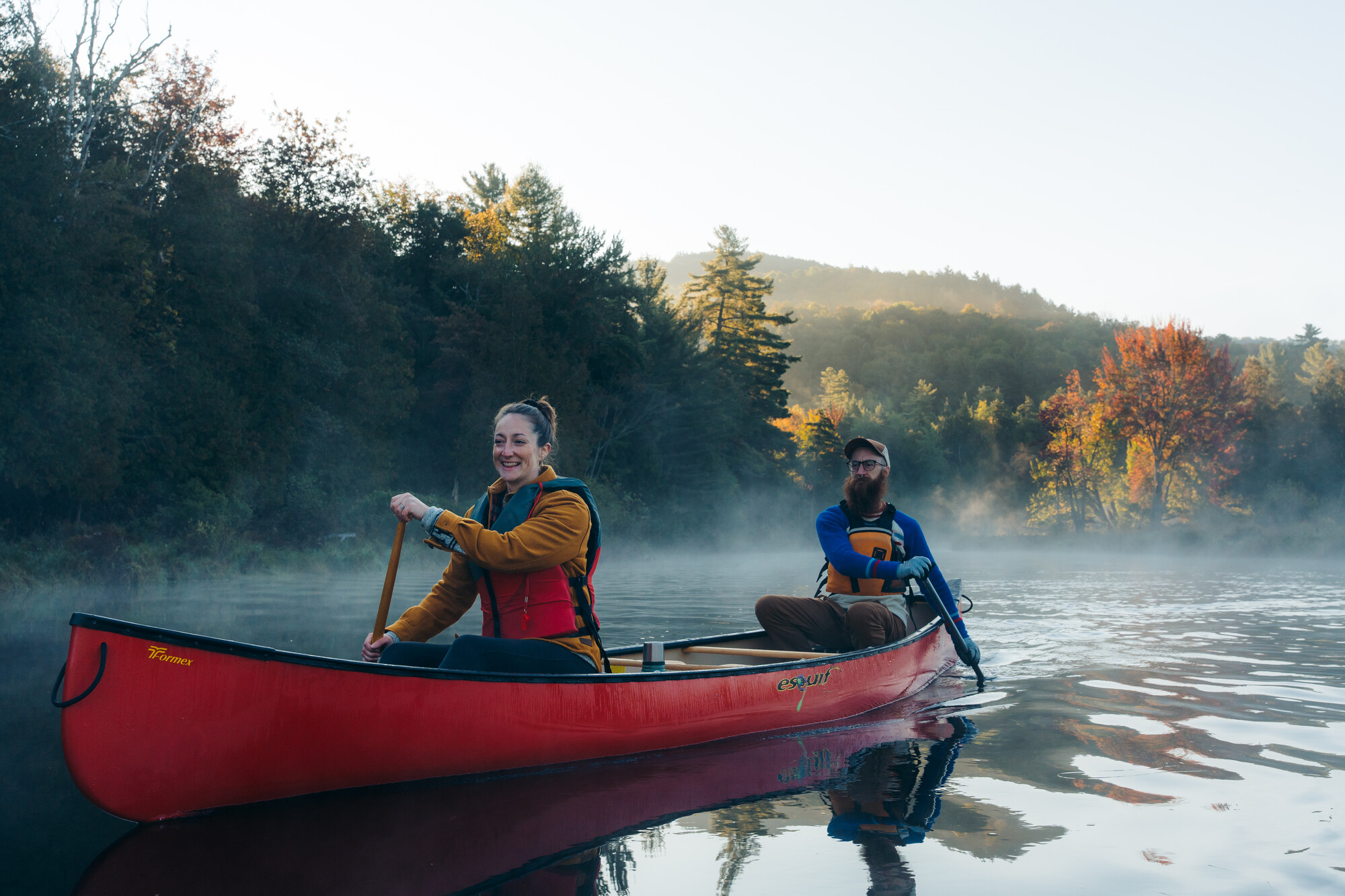 Two people paddling in a red canoe