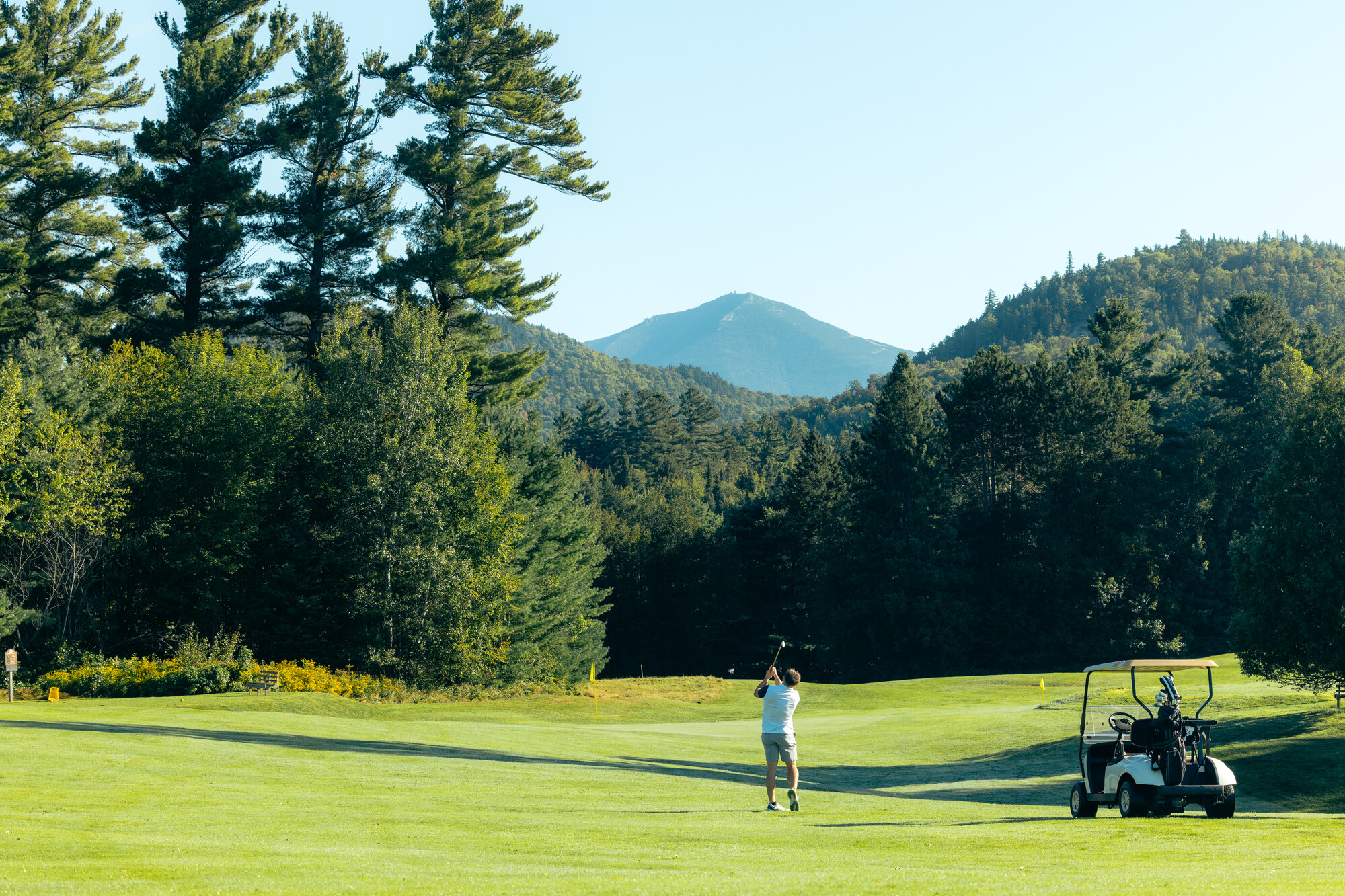 A golfer on a course below the mountains