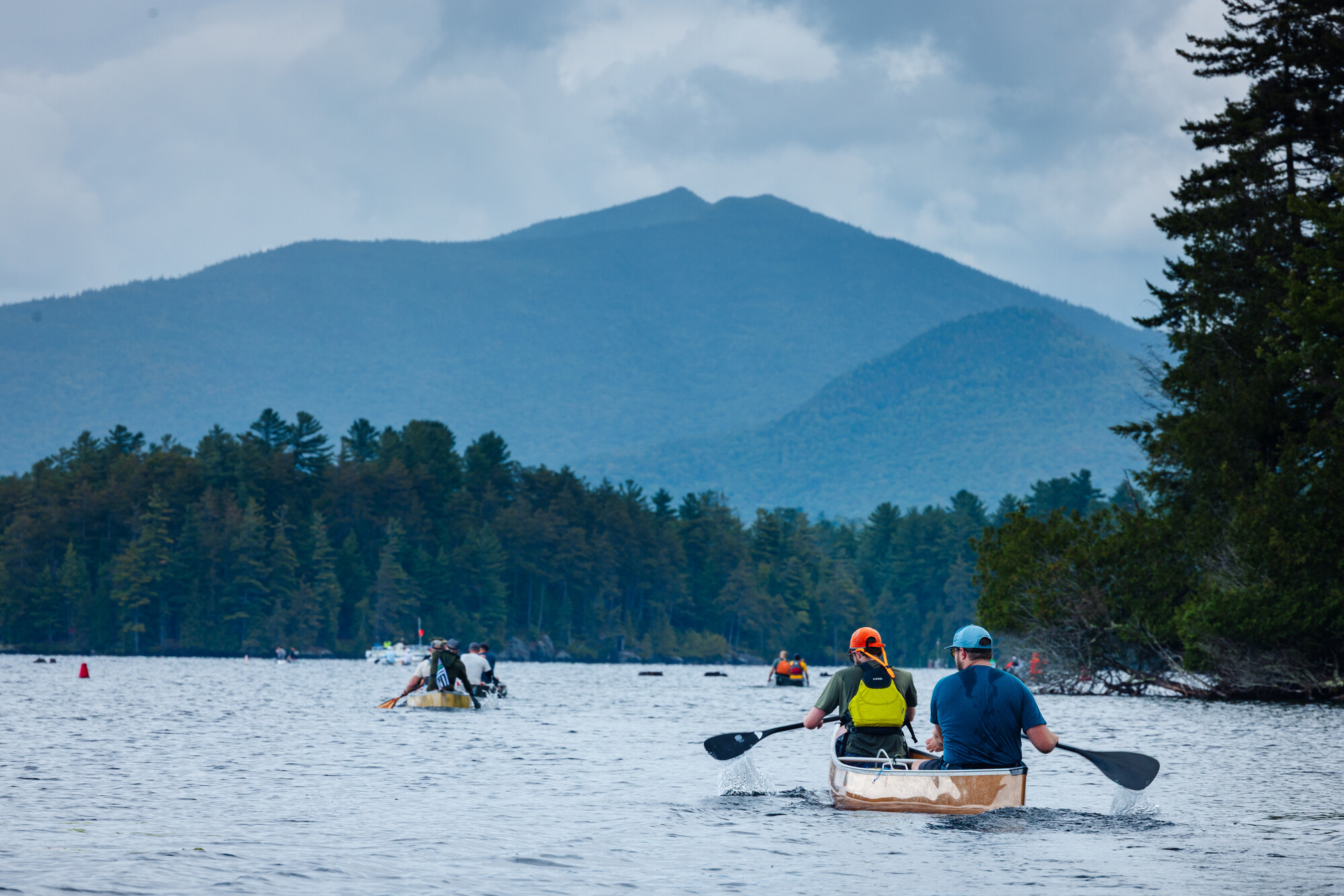 Canoes paddle towards a soaring Adirondack mountain.