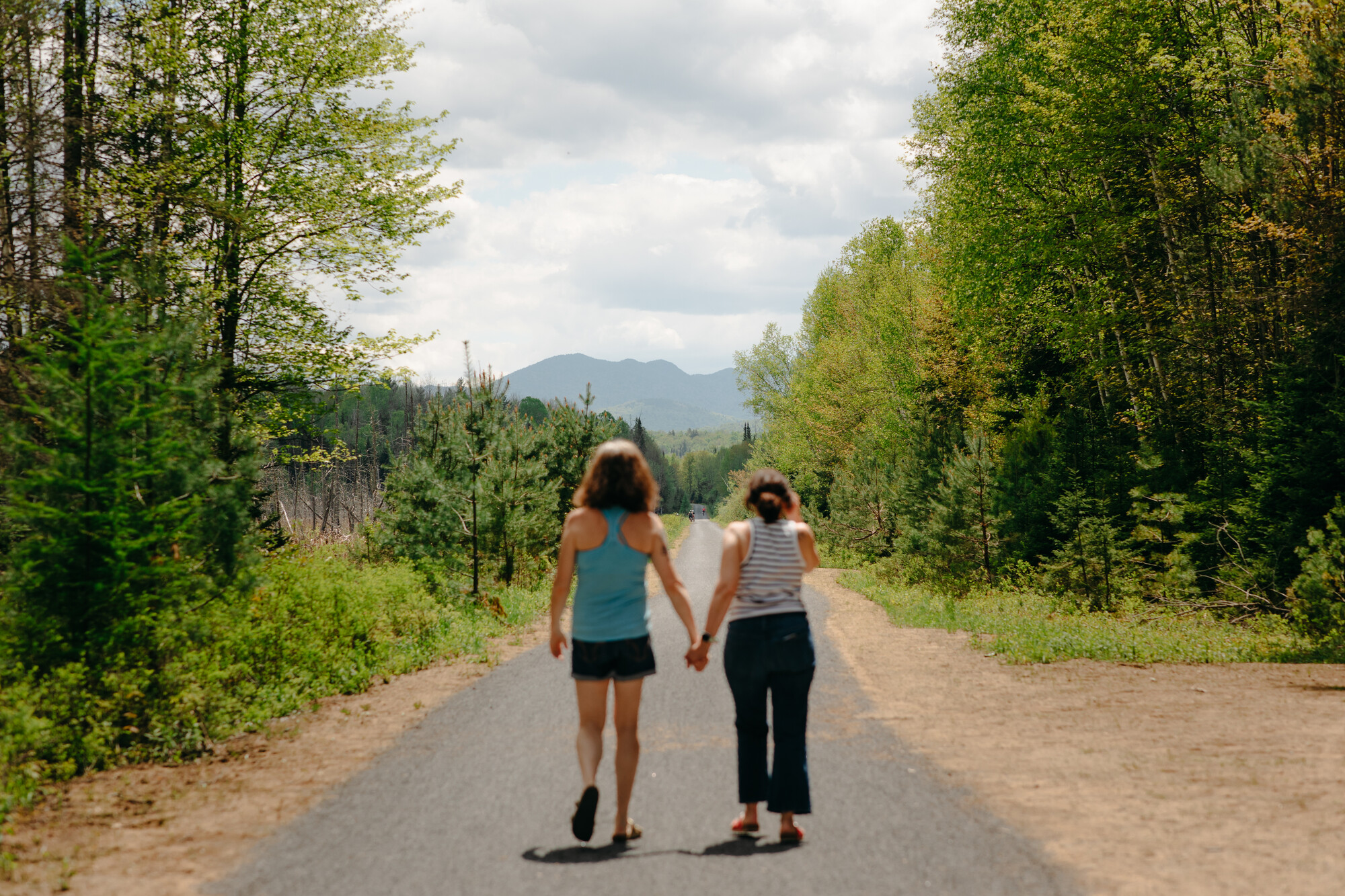 two women walk on a nature path in the wilderness. 