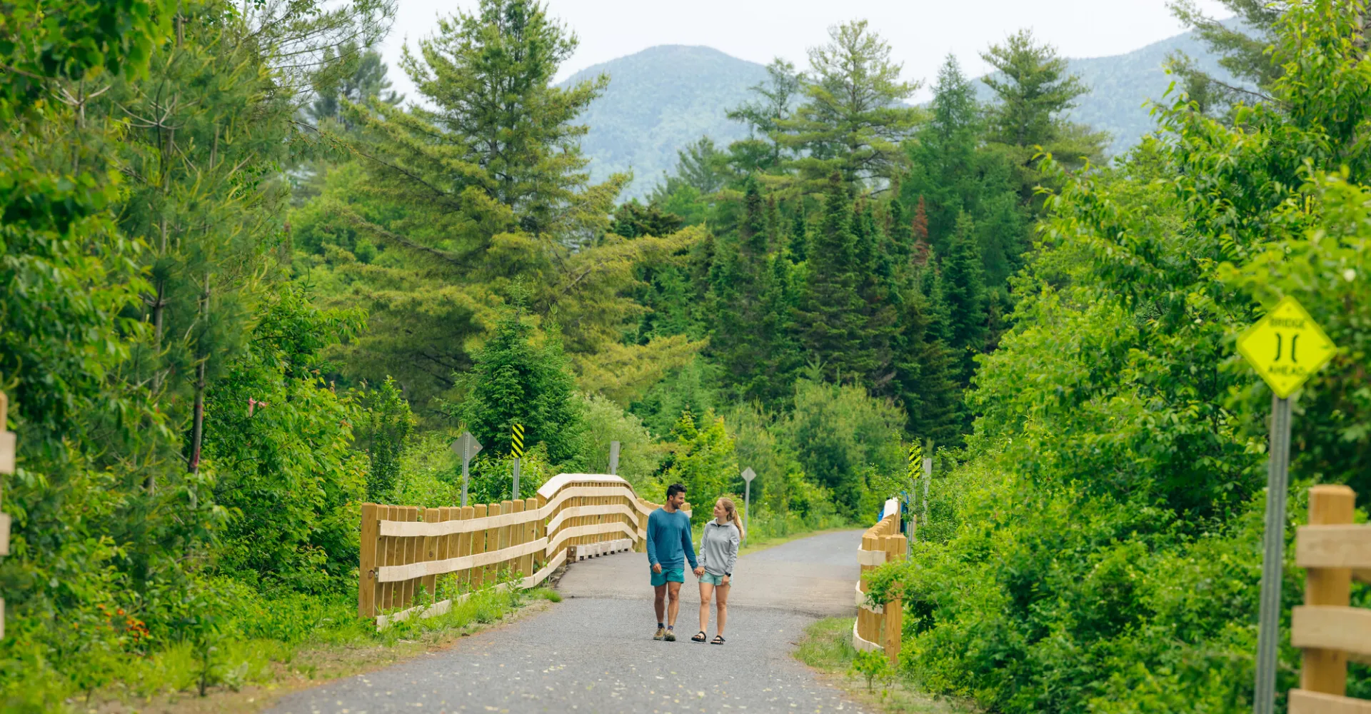 A couple walking on the Adirondack Rail Trail in the summer.