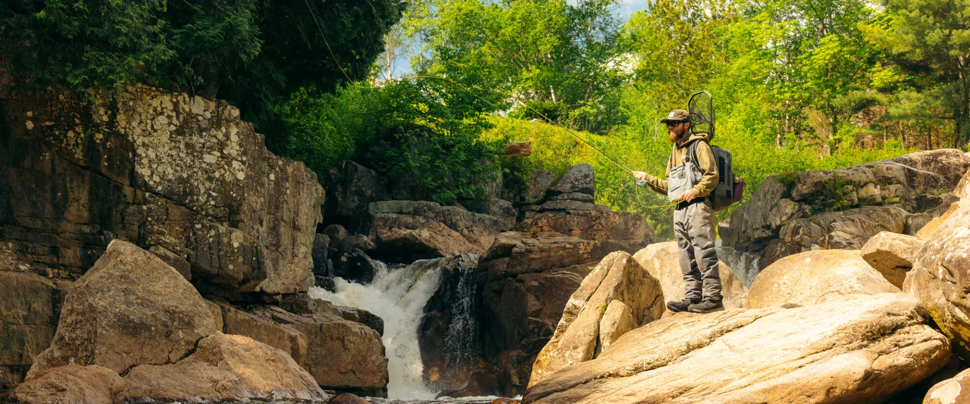 A fly fisher on a rock by the water