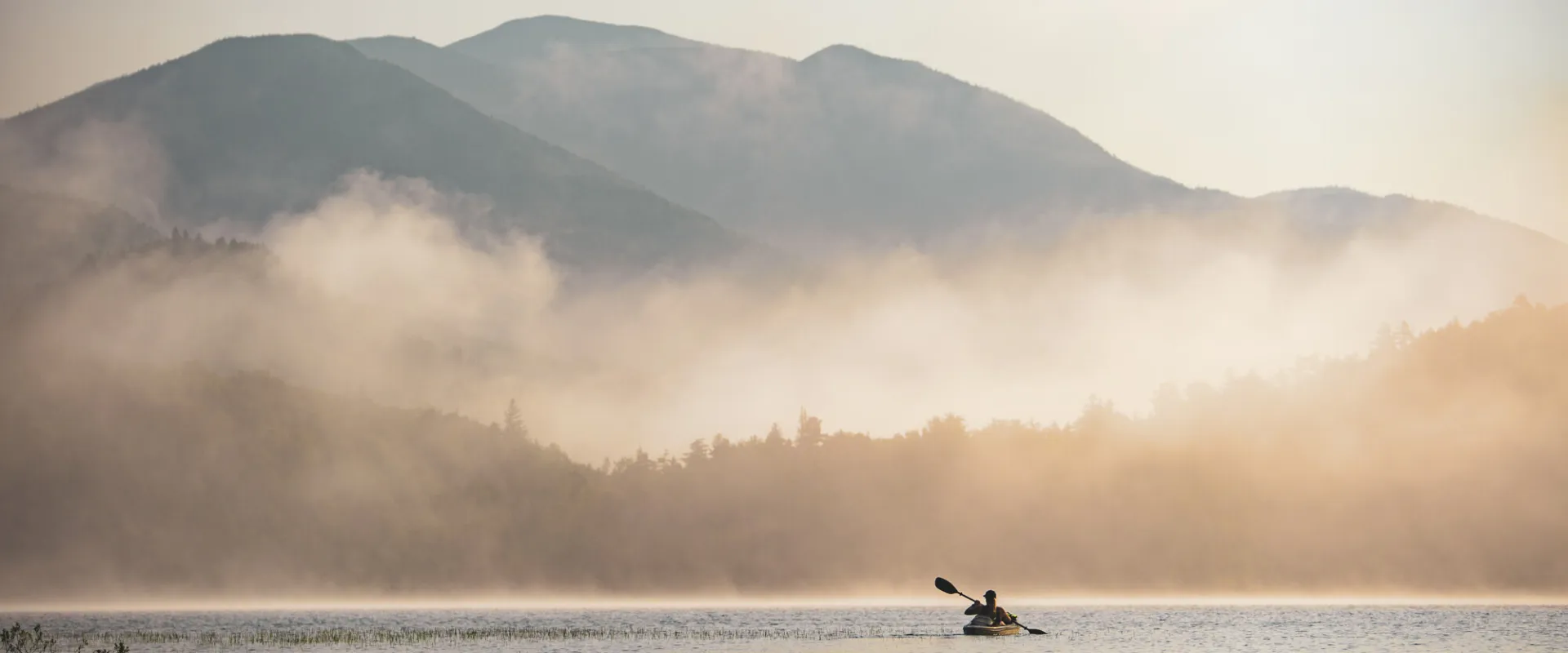 A paddler in front of some misty mountains