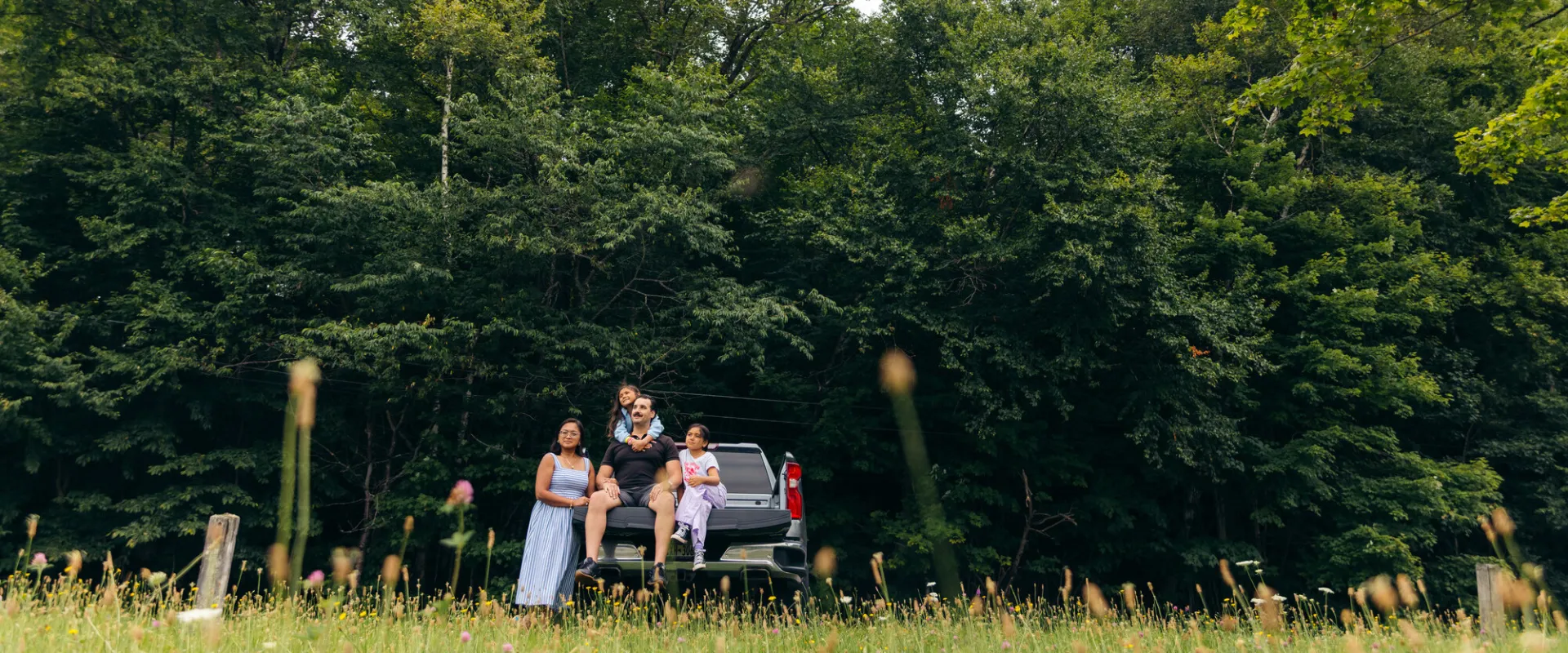 A family sitting on the back of a truck