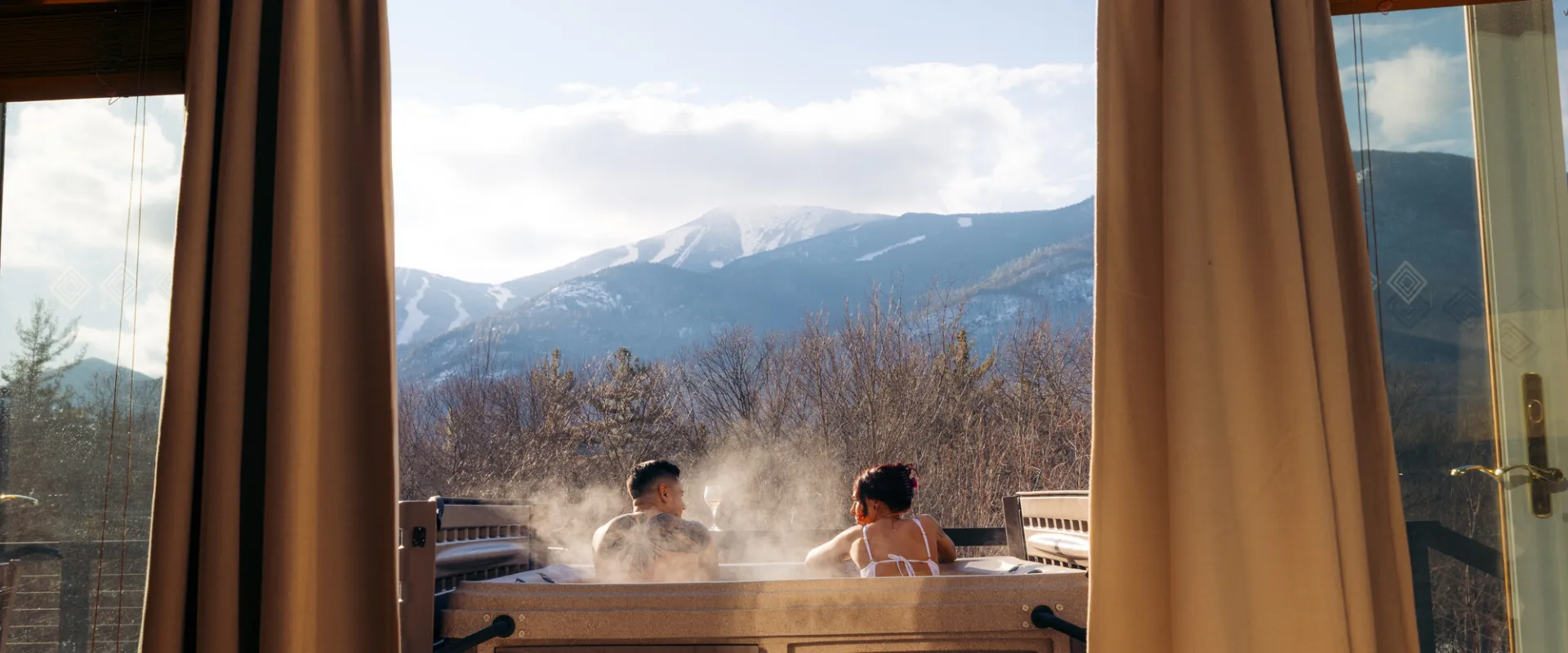 Two people in a hot tub overlooking a ski mountain