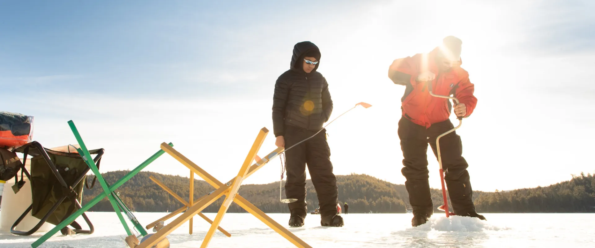Two men ice fishing with tip ups in front of them