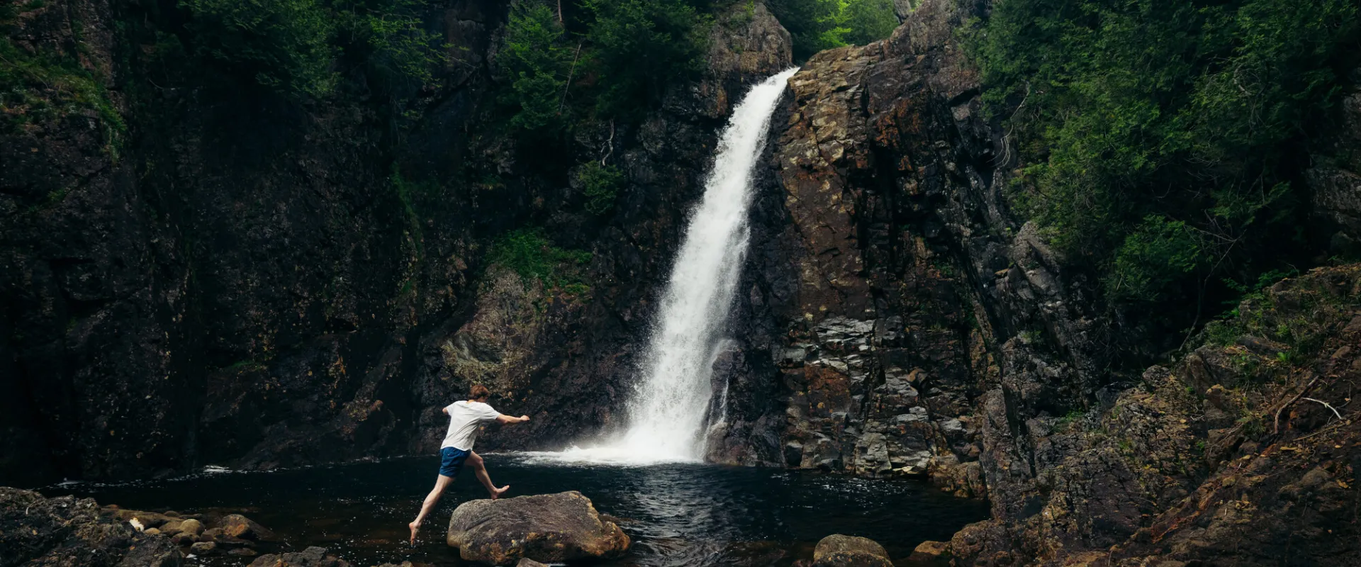 A man jumping near a waterfall