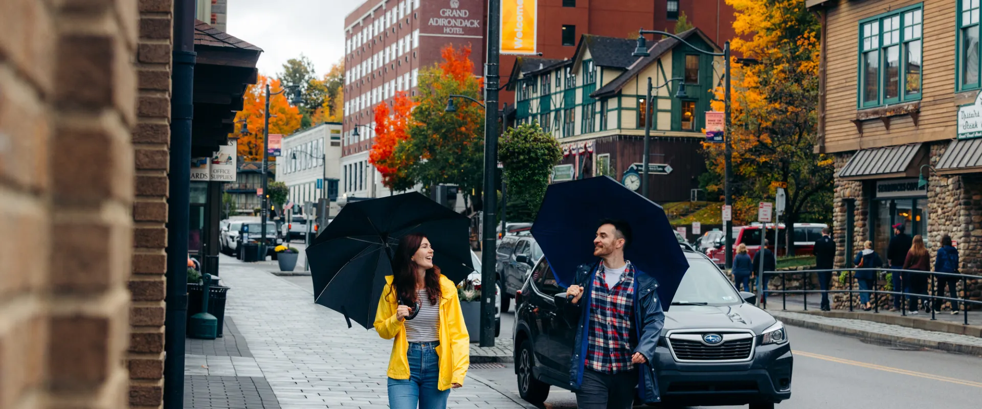 A man and woman walk on a main street of a small town in fall. 