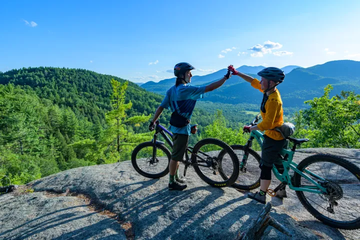 Two mountain bikers high-fiving in the Lake Champlain Region