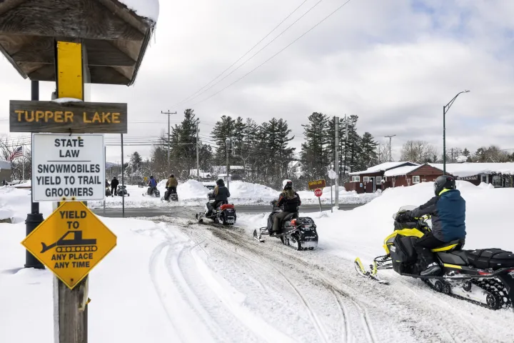 Snowmobilers crossing the road in Tupper Lake