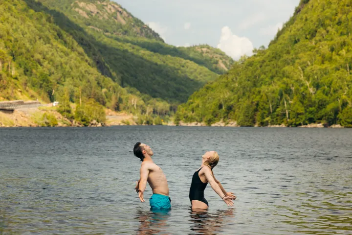 Two people in a lake between tall mountains