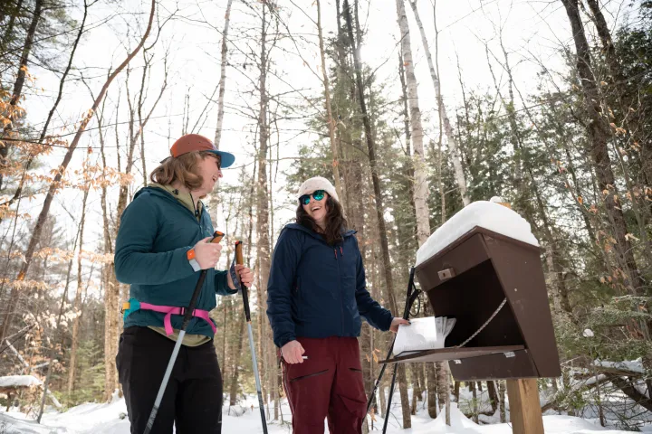 Two xc skiers signing into a register
