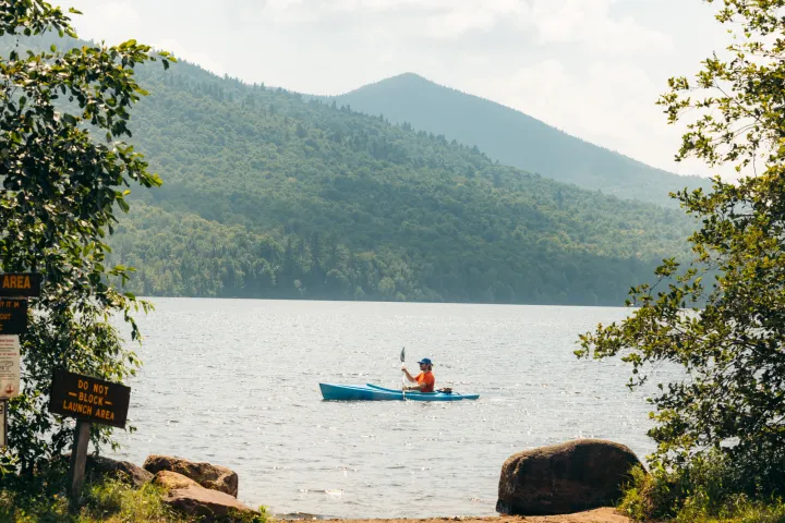 A paddler in front of a beach area in the mountains