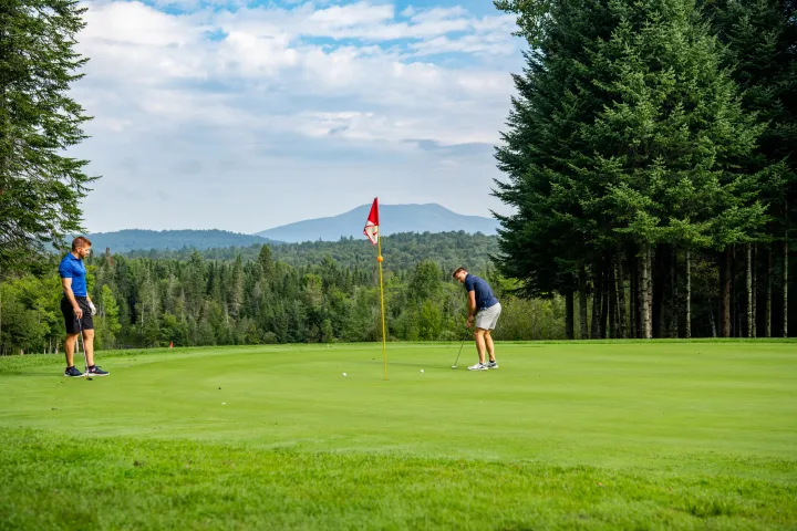 Two golfers on a golf course with a mountain view