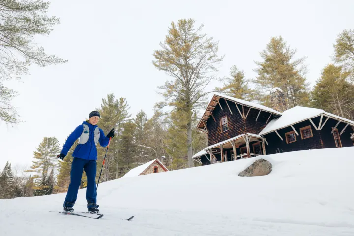 A xc skier near a historic log building