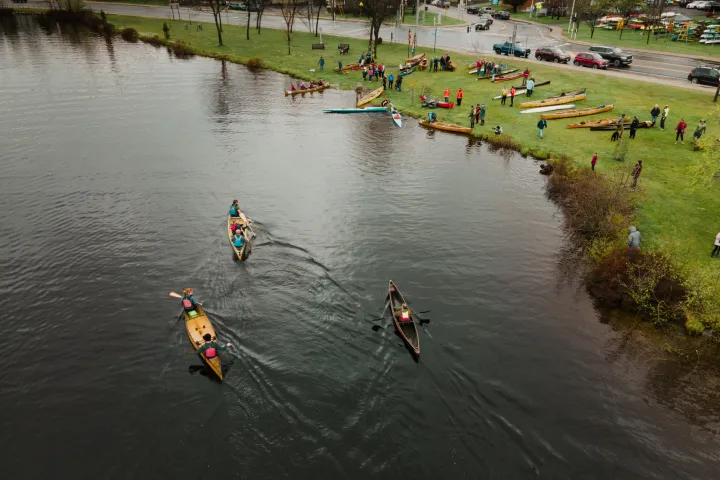 Dozens of paddlers on the banks of a river