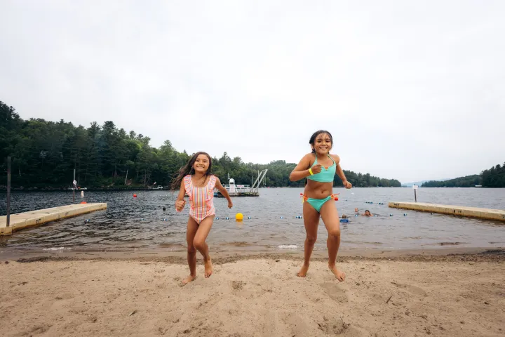 A couple kids running out of the water at a beach