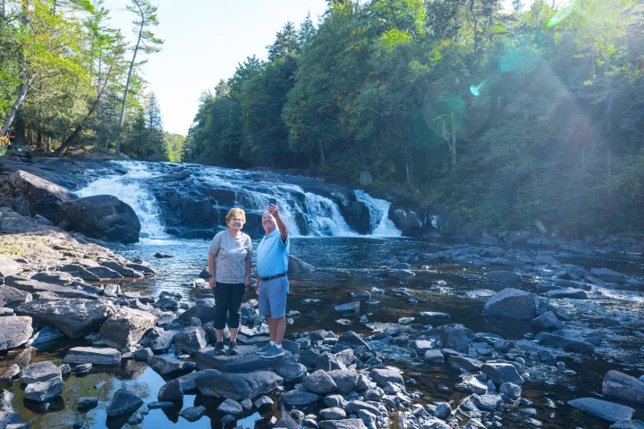 An older couple in front of a waterfall