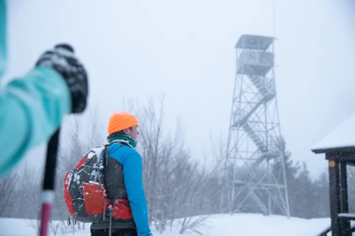 Snowshoers looking up at a firetower