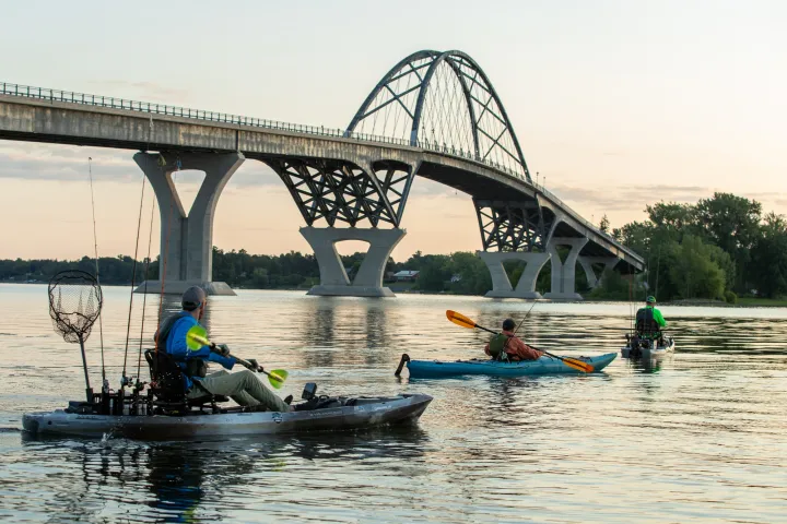 Kayak fishers on Lake Champlain in front of a large bridge