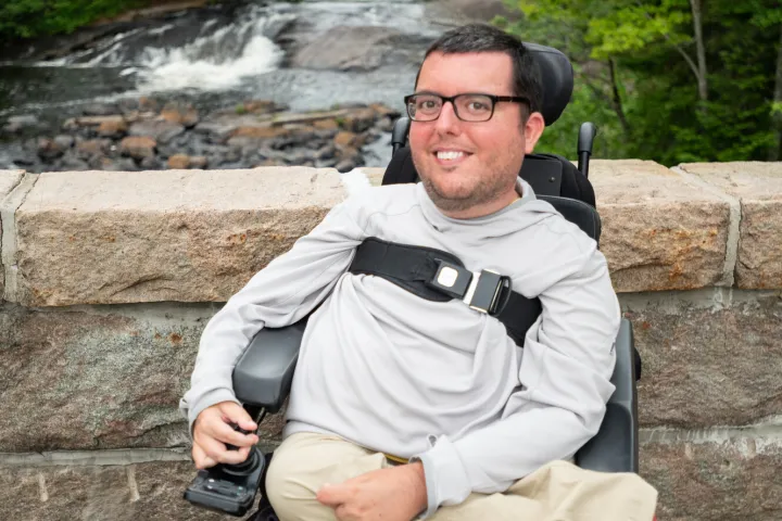 A person in a wheelchair at a bridge over a waterfall