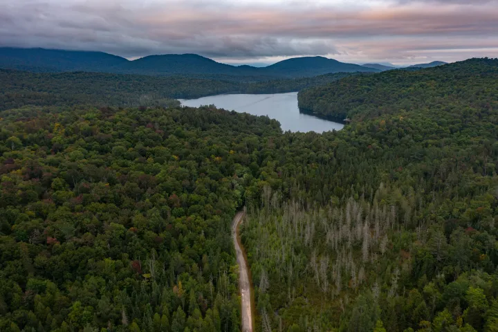A dirt road leading to a huge pond among mountains
