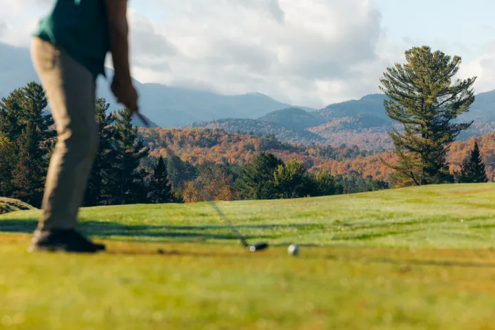 A golfer about to swing, with a backdrop of fall leaves