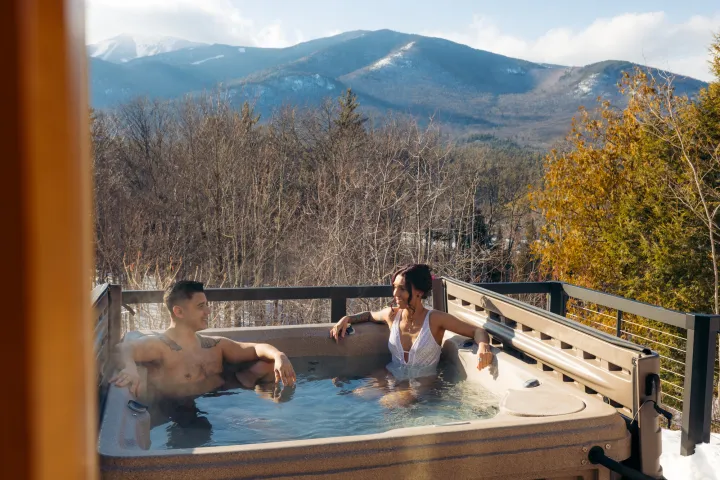Two people in a hot tub overlooking snowy mountains
