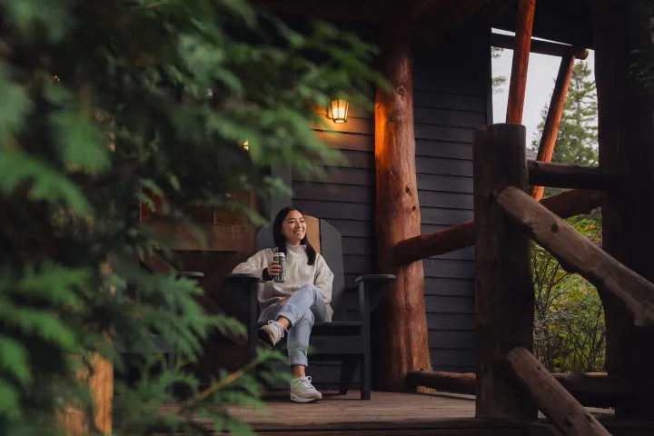 A woman lounging on the front porch of a cabin
