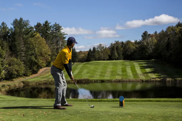 A golfer looking out over a mid-course pond