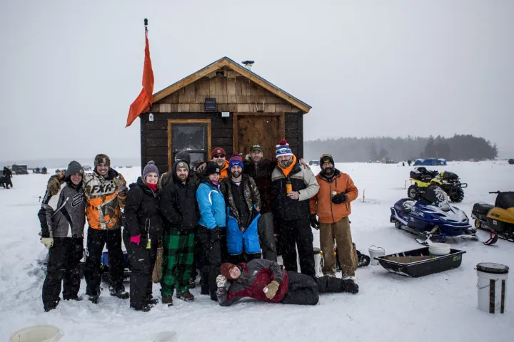 A group of ice fishers by a wooden shanty