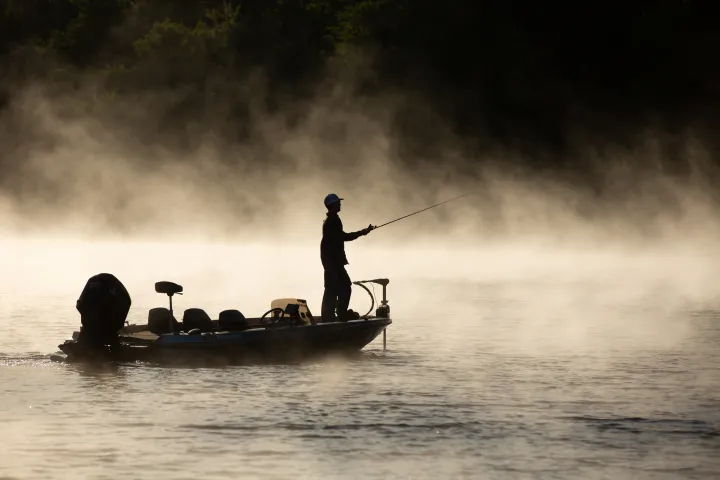 The silhouette of a fisherman on a boat in the morning