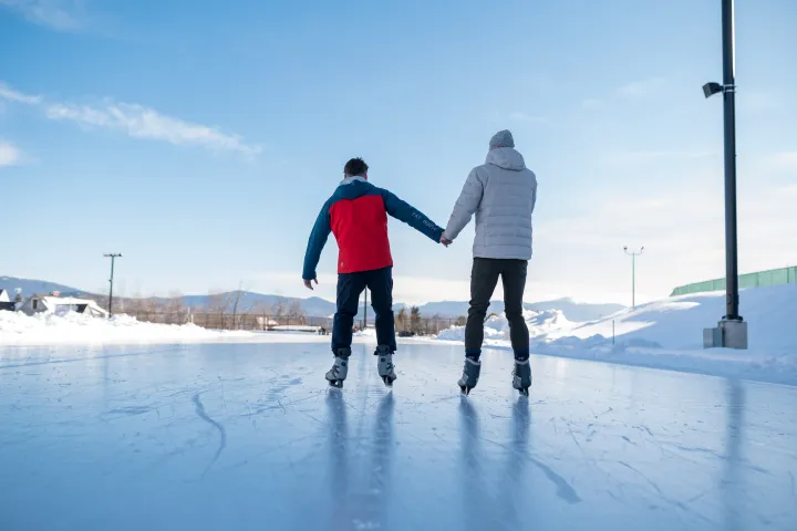 Two people skating on an outdoor ice oval