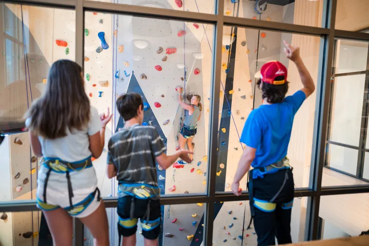 Kids cheer on their mom climbing indoors