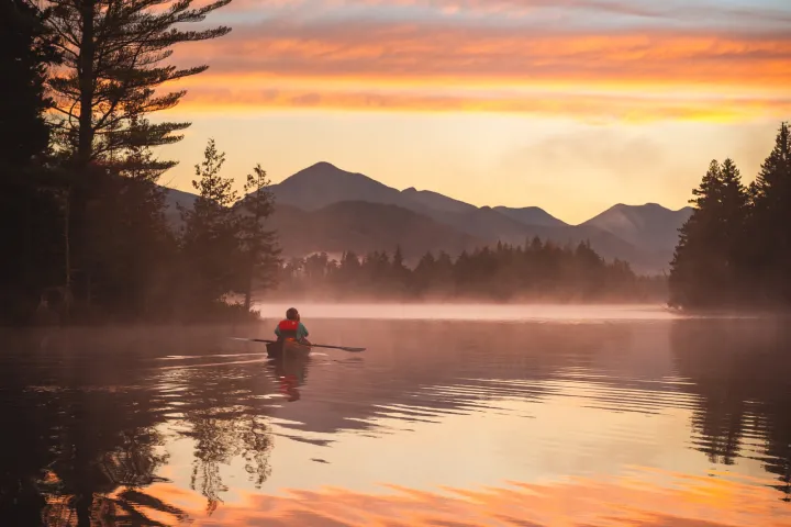 Someone paddling on a large lake during sunrise