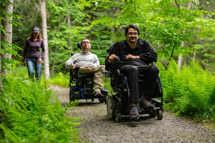 Two people on a trail in wheelchairs