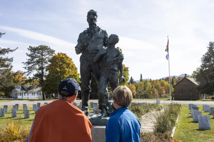 Two people looking at a statue of John Brown and a young kid