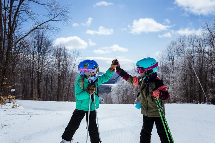 Kids high fiving on a ski hill