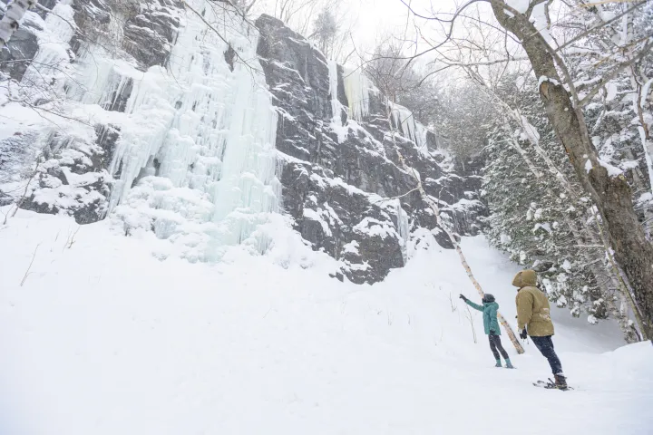 Two snowshoers looking at a frozen waterfall