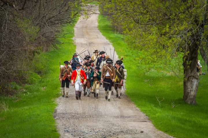 Revolutionary War reenactors walking through an orchard